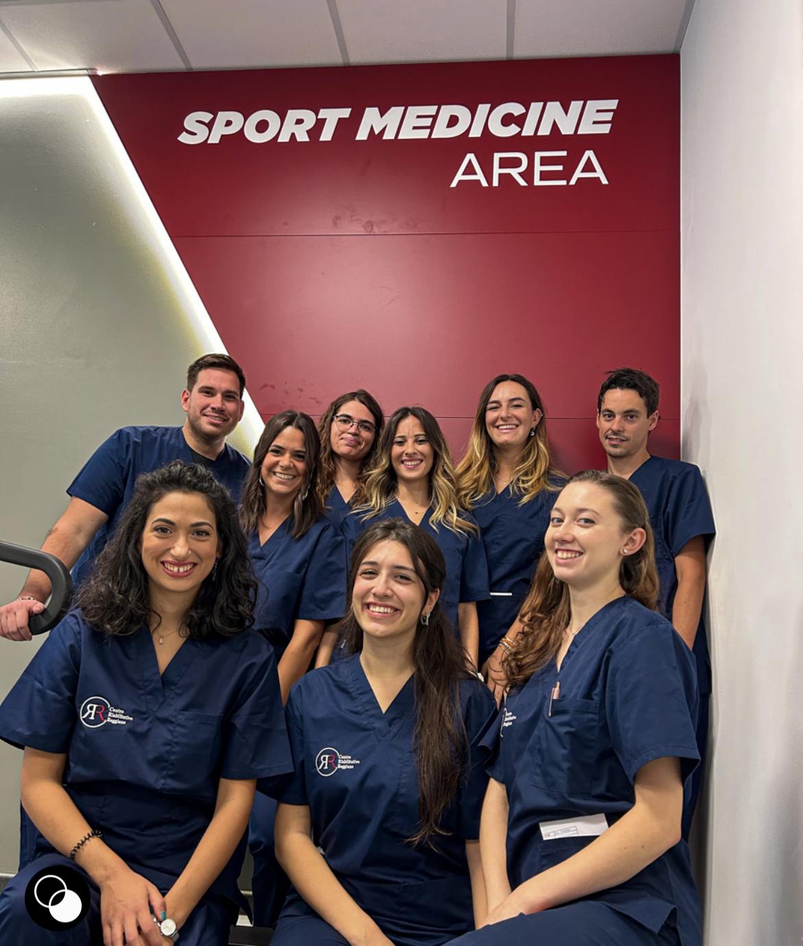 I fisioterapisti del Centro Medico Reggiano sotto la parete con la scritta Sport Medicine Area nella palestra del Centro Medico Reggiano