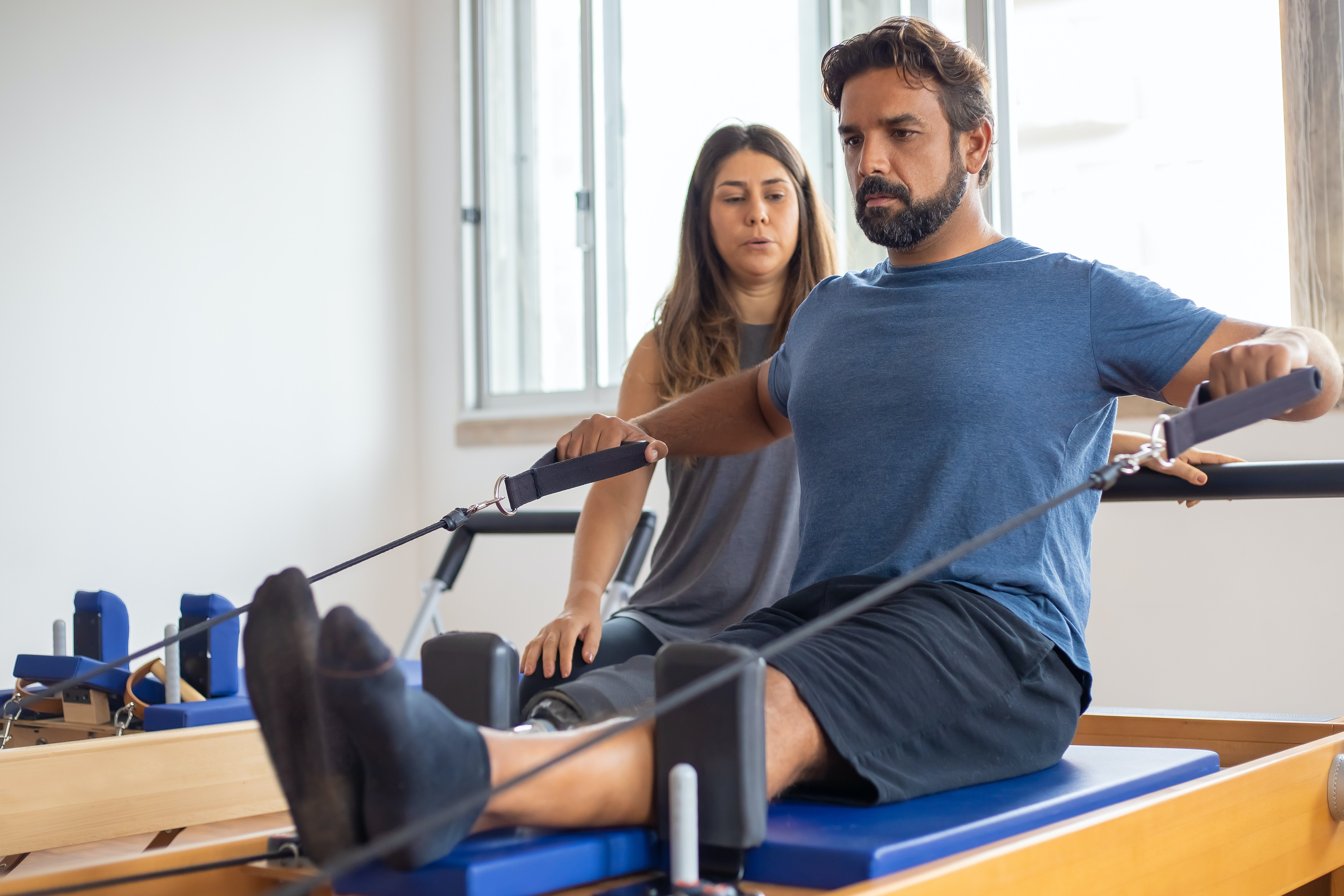 Uomo con protesi alla gamba svolge pilates su lettini reformer