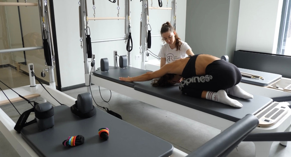Fisioterapista che controlla la corretta esecuzione dell'esercizio durante una lezione di Pilates-Pro